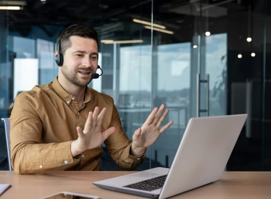 Online consultation, hotline support service. A young man sits in the office in a headset and talks